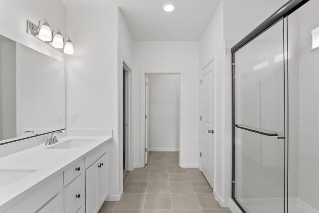 bathroom featuring double vanity, a shower stall, a sink, and tile patterned flooring