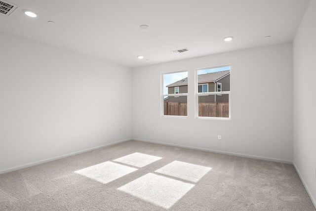empty room featuring carpet, recessed lighting, and visible vents