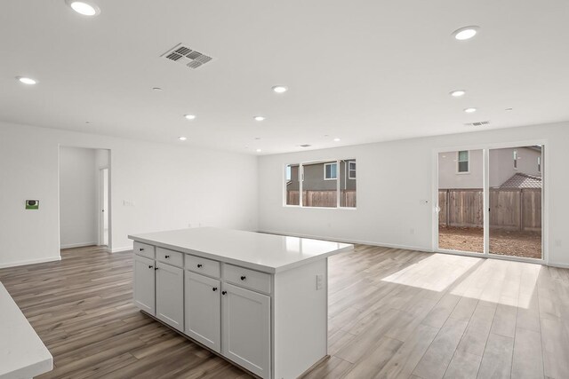 kitchen with a kitchen island, visible vents, light wood-type flooring, baseboards, and recessed lighting