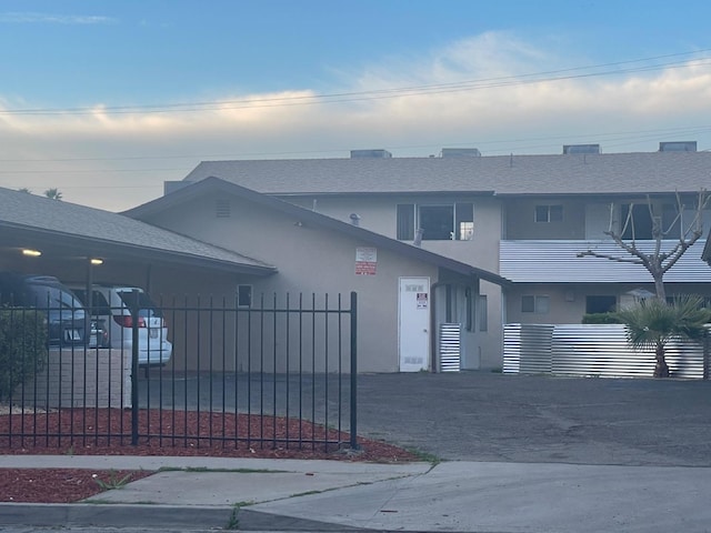 view of property with stucco siding, roof with shingles, and fence