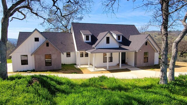 modern inspired farmhouse with covered porch, board and batten siding, and a shingled roof