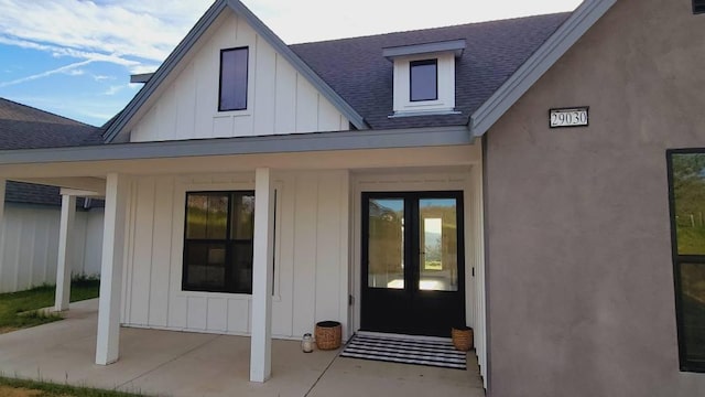 property entrance featuring a patio, board and batten siding, and roof with shingles