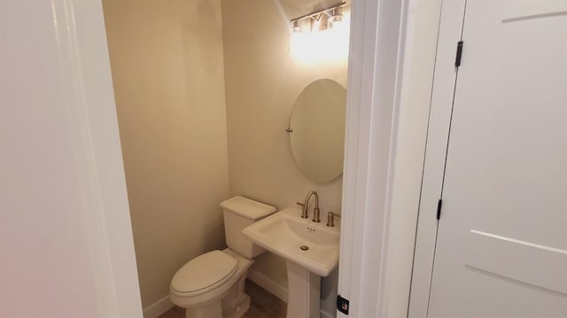 half bath with a sink, baseboards, and toilet