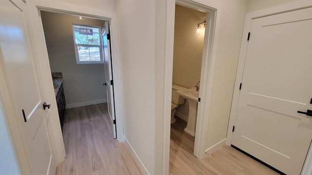 hallway featuring light wood-style flooring and baseboards