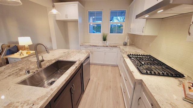 kitchen with under cabinet range hood, white cabinets, appliances with stainless steel finishes, and a sink