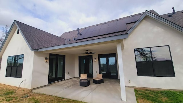 back of property with roof with shingles, ceiling fan, french doors, a patio area, and roof mounted solar panels