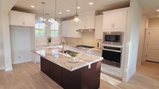 kitchen featuring white cabinetry, a center island with sink, under cabinet range hood, and stainless steel appliances