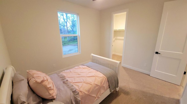 bedroom featuring a walk in closet, carpet, and baseboards