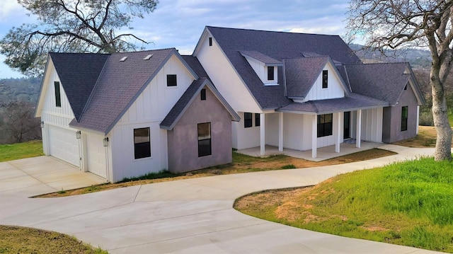 modern farmhouse with driveway, covered porch, board and batten siding, an attached garage, and roof with shingles