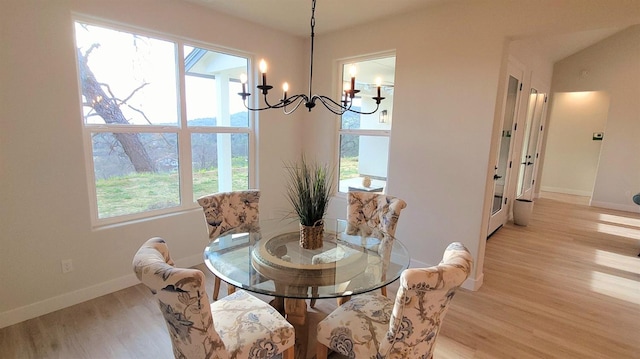 dining room featuring baseboards, light wood-style floors, and an inviting chandelier