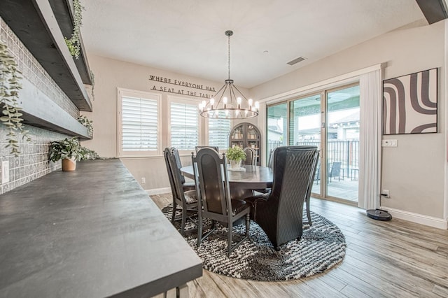 dining room with visible vents, a notable chandelier, baseboards, and wood finished floors