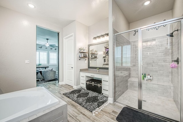 full bath featuring a stall shower, wood finished floors, vanity, and a bath