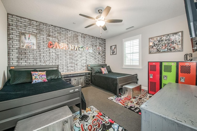 bedroom with visible vents, an accent wall, a ceiling fan, carpet flooring, and brick wall