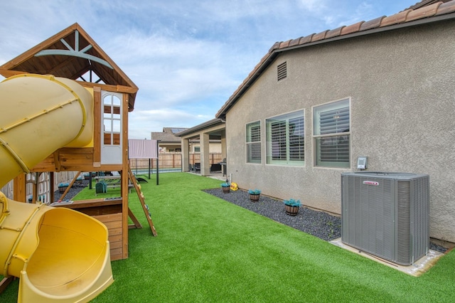 view of yard featuring a playground, fence, and central air condition unit