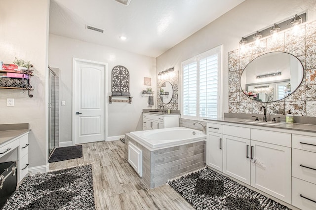 bathroom with wood finished floors, two vanities, a sink, visible vents, and a shower stall