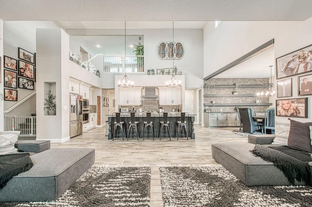 living room with light wood-style floors, a high ceiling, and a notable chandelier