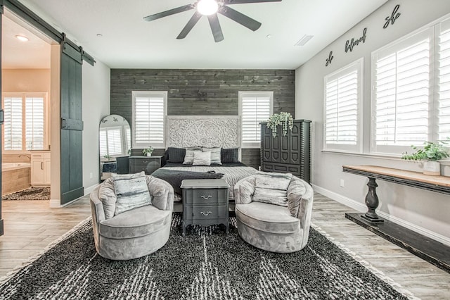 living room featuring an accent wall, a wealth of natural light, wood finished floors, and a barn door