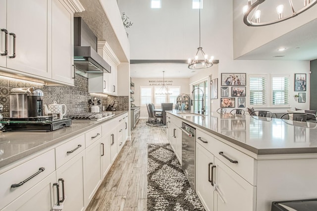 kitchen featuring light wood finished floors, stainless steel appliances, tasteful backsplash, a sink, and a chandelier