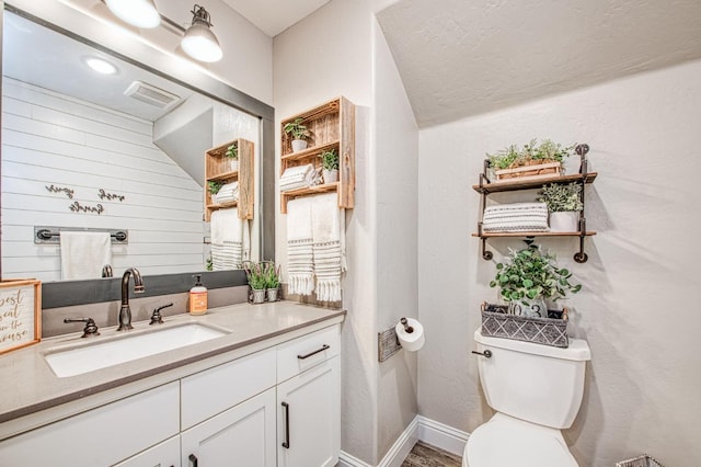 bathroom with visible vents, vanity, toilet, and baseboards