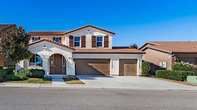 mediterranean / spanish-style home with driveway, a tiled roof, and stucco siding