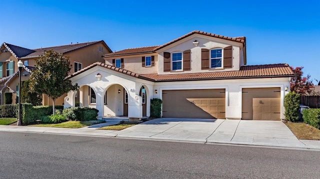 mediterranean / spanish-style home with a garage, a tile roof, driveway, and stucco siding