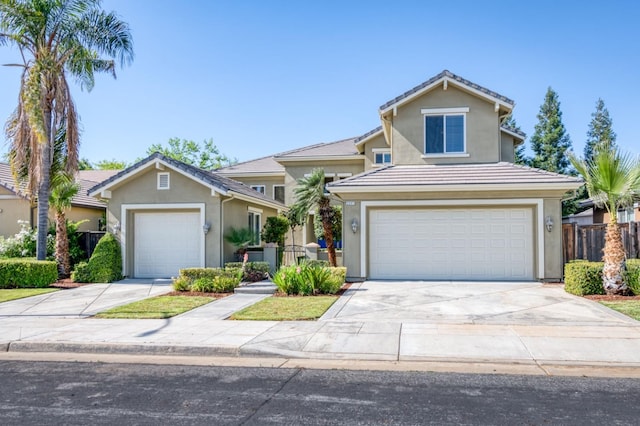 view of front of house with driveway, fence, and stucco siding