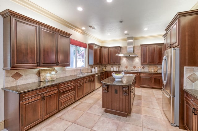 kitchen with visible vents, wall chimney exhaust hood, appliances with stainless steel finishes, dark stone countertops, and a kitchen island with sink