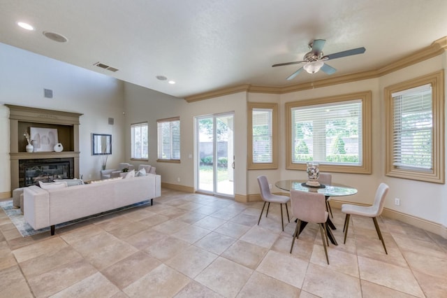 dining space with light tile patterned floors, baseboards, visible vents, a glass covered fireplace, and crown molding