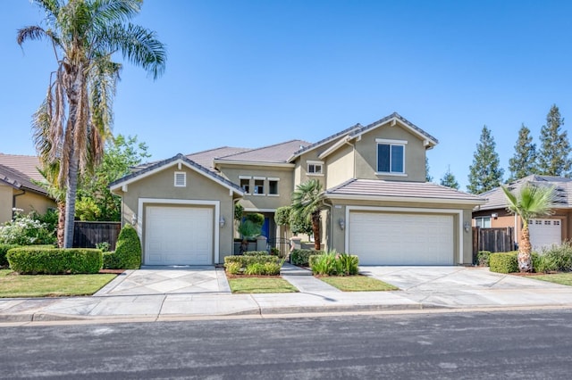 traditional-style home with a garage, concrete driveway, fence, and stucco siding