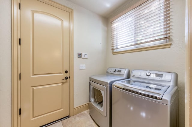 washroom with laundry area, light tile patterned floors, baseboards, and independent washer and dryer