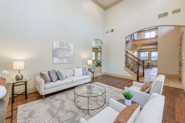 living room featuring arched walkways, visible vents, stairway, and wood finished floors