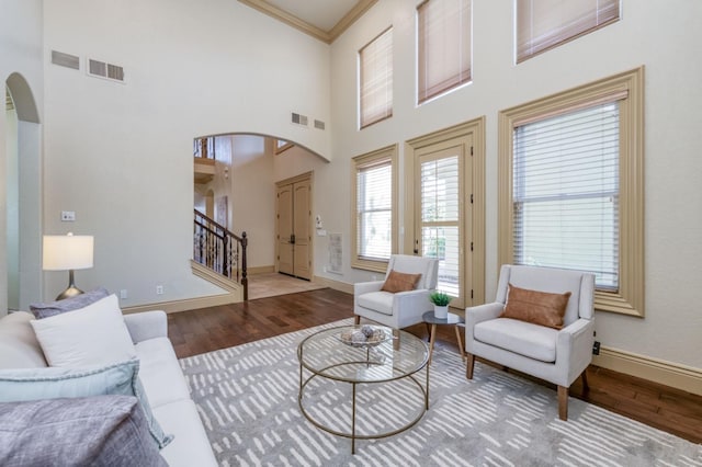 living room with visible vents, stairs, arched walkways, and wood finished floors