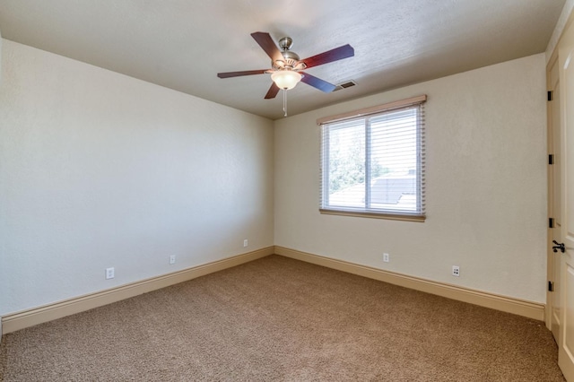 carpeted spare room with baseboards, visible vents, and a ceiling fan