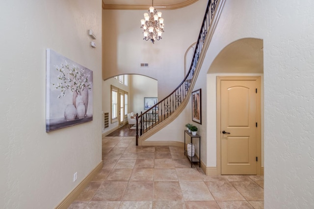 foyer entrance with arched walkways, stairs, visible vents, and baseboards