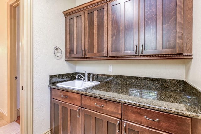 kitchen with dark stone countertops and a sink