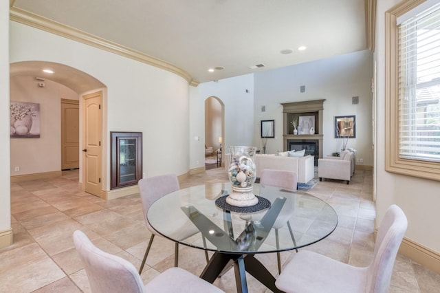 dining space with arched walkways, visible vents, a glass covered fireplace, and a wealth of natural light