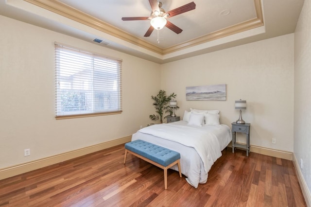 bedroom featuring a raised ceiling, visible vents, crown molding, and wood finished floors