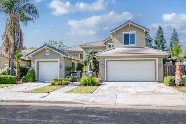 traditional home featuring a garage, concrete driveway, fence, and stucco siding