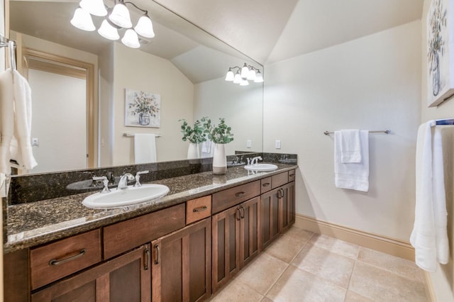 bathroom with tile patterned flooring, vaulted ceiling, a sink, and double vanity