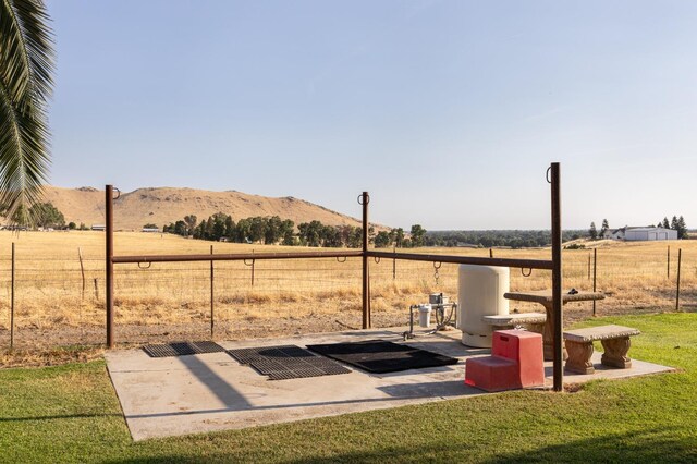 view of yard featuring fence, a mountain view, and a rural view