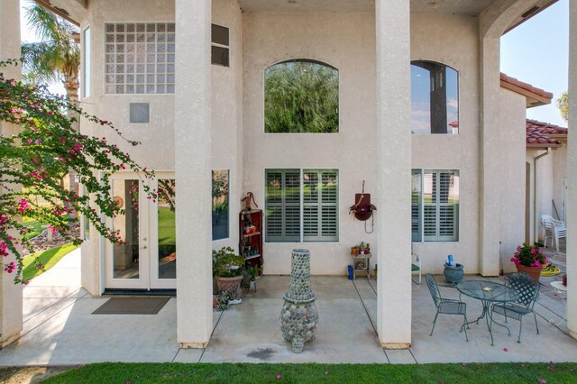 back of property with stucco siding, a tile roof, french doors, and a patio