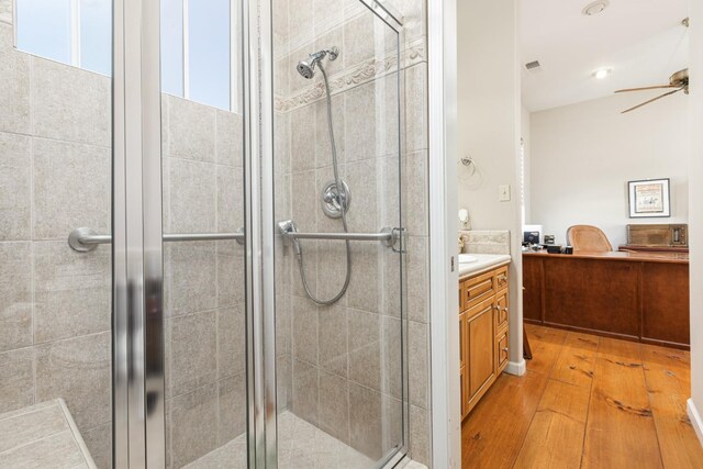 bathroom featuring ceiling fan, wood finished floors, visible vents, vanity, and a stall shower