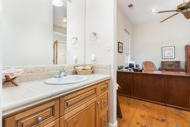 bathroom with hardwood / wood-style flooring, ceiling fan, visible vents, and vanity