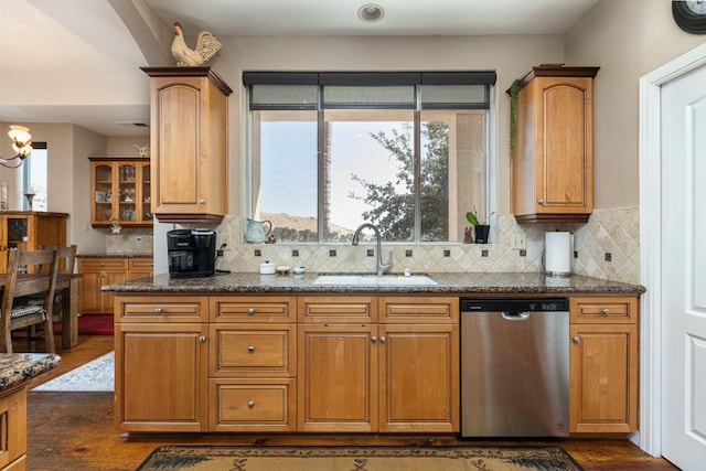 kitchen with brown cabinetry, a sink, stainless steel dishwasher, and tasteful backsplash