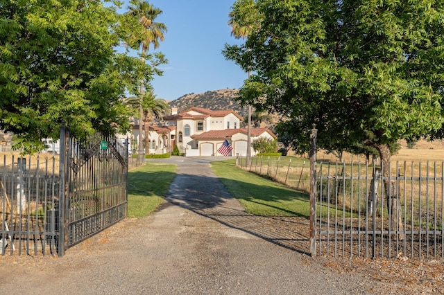 view of front facade featuring a garage, driveway, a front lawn, and fence