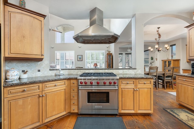 kitchen featuring island exhaust hood, backsplash, dark wood-type flooring, dark stone countertops, and luxury stove