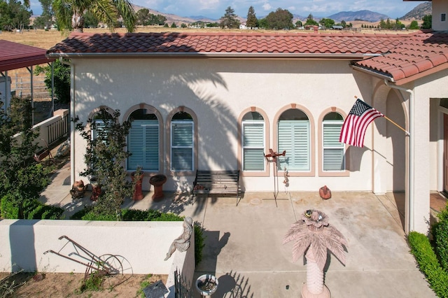 view of side of property with a tiled roof, a mountain view, and stucco siding