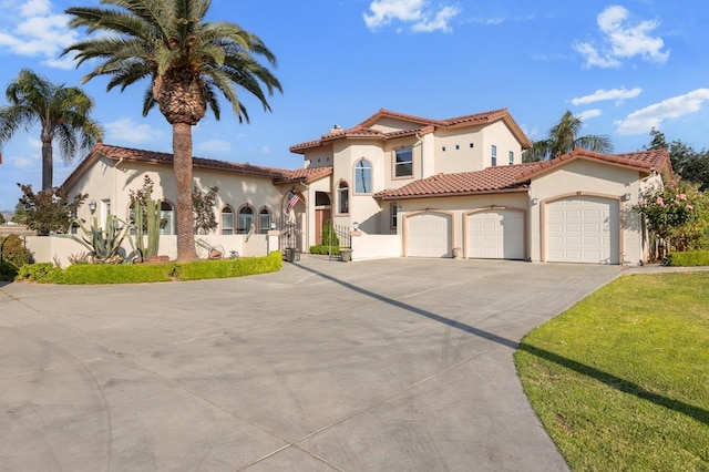 mediterranean / spanish-style house with a tile roof, stucco siding, concrete driveway, an attached garage, and a front yard