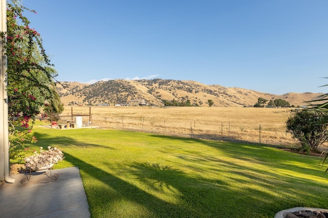 view of yard with fence, a mountain view, and a rural view