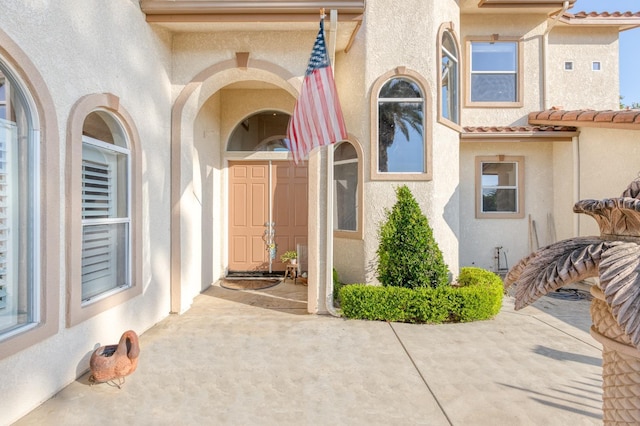 property entrance featuring a tile roof and stucco siding